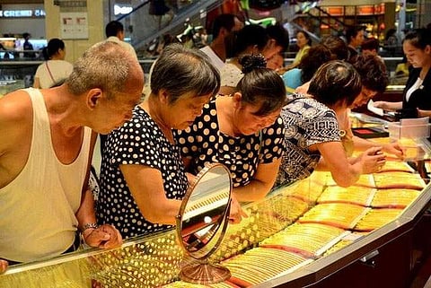 Customers look at gold necklaces at a jewelry store in Xuchang, Henan province, August 12, 2015. (Reuters)