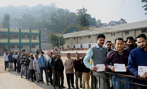 Voters in a queue show their voter identity card at a polling booth in Mandi, Himachal Pradesh. (PTI)