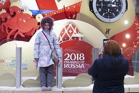 A girl poses for a photo in front of a clock counting down to the first match of the 2018 World Cup, which is installed on Manezh Square, outside the Kremlin in Moscow, Russia, Thursday, Nov. 30, 2017. | AP