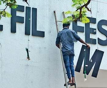 A man makes a move to fix the letter ‘M‘ on the IFFK sign board  at Tagore Theatre