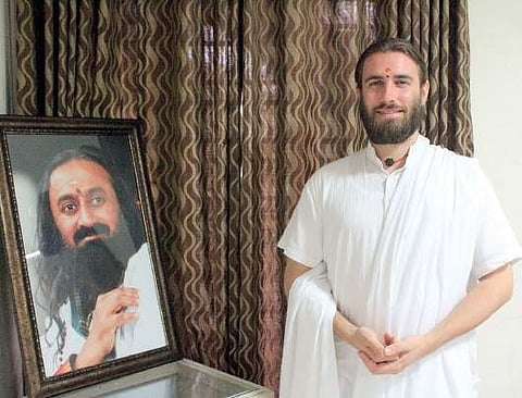 Swami Purnachaitanya besides a photograph of Sri Sri Ravi Shankar  Jainth Thomas Joseph