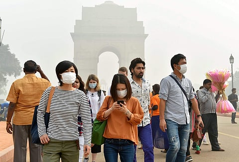 People wear masks to protect themselves from smog and air pollution that reached high levels at Rajpath in New Delhi | PTI