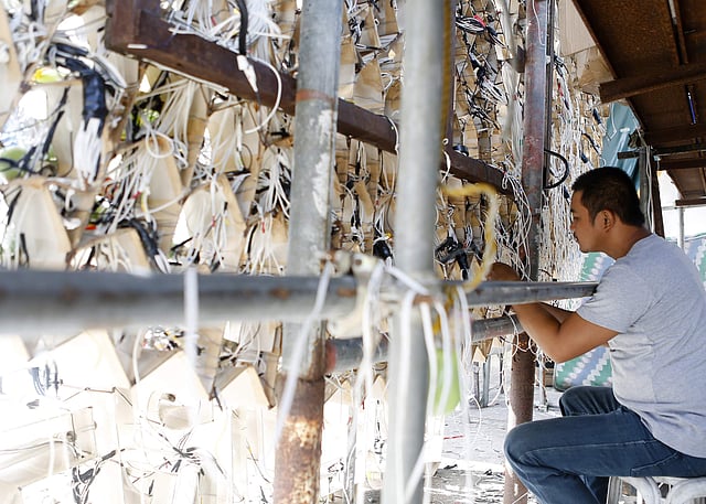 The lanterns stand as tall as 20 feet and illuminated by about 3,500 to 5,000 light bulbs. In pic: A lantern maker works on the wiring of a giant lantern. (Photo| AP)