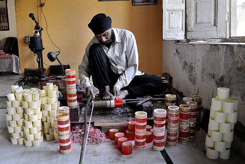 The Choora is worn by a newly wed punjabi bride (it is mandatory for them) on the day of her marriage. In pic: Amritsar Craftsman Gurcharan Singh cutting the coloured Choora wedding bangles for packaging at his workshop in Amritsar. (Photo | PTI)