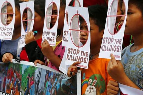 Protesters peer from cutouts which show portraits of killed activists during a rally outside the armed forces headquarters to protest the recent killings of peasant and religious leaders Wednesday, Dec. 6, 2017 in suburban Quezon city northeast of Manila,