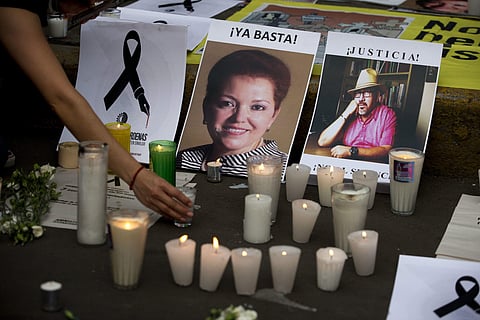 In this May 16, 2017, file photo, a woman places a candle in front of pictures of murdered journalists Miroslava Breach, left, and Javier Valdez during a demonstration against the killing of journalists, outside the Interior Ministry in Mexico City. (Phot