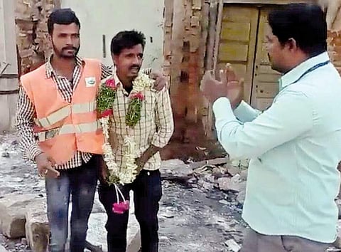 A GHMC staffer claps for a man after he was garlanded for urinating in the open at Koti in Hyderabad | Express
