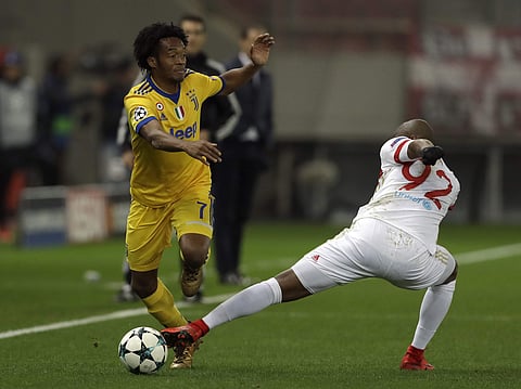 Juventus' Juan Cuadrado, left, challenges for the ball with Olympiakos' Seba during the Champions League group D soccer match between Olympiakos and Juventus at Georgios Karaiskakis stadium at Piraeus port. | AP