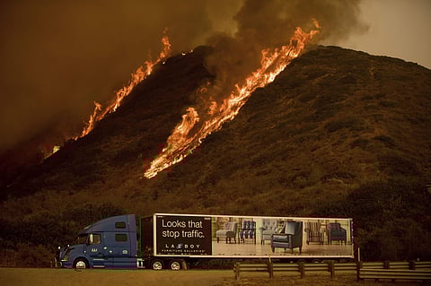 Flames from the Thomas fire burn above a truck on Highway 101 north of Ventura, Calif., on Wednesday, Dec. 6, 2017. (AP Photo)