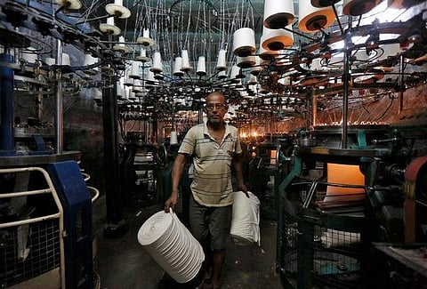 An employee carries cloth rolls inside an undergarment factory in Kolkata, India, February 1, 2017. | Reuters