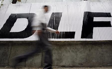 A man walks past a logo of Indian property developer DLF Ltd. in Mumbai. (File Photo | Reuters)
