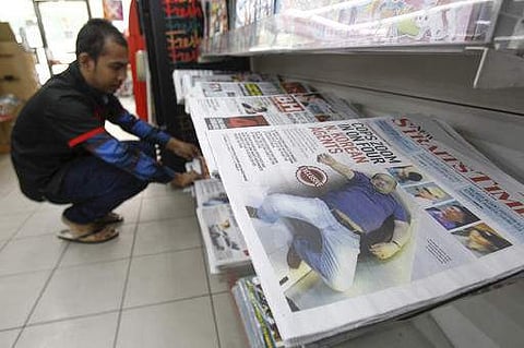 A man arranges a newspaper carrying Kim Jong-nam's death investigation report in Malaysia. (Photo | AP)