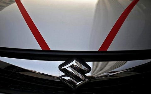 The logo of Maruti Suzuki India Limited is seen on car parked outside a showroom in New Delhi, India. | Reuters