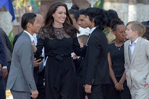 Hollywood star Angelina Jolie (3rd L) and her children including Maddox Jolie-Pitt (C) gesture to media in front of the royal residence for a meeting with Cambodian King Norodom Sihamoni in Siem Reap on February 18. (Photo | AFP)