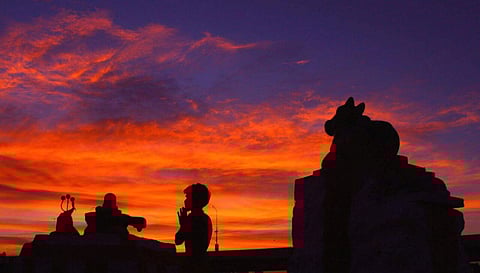 A devotee in Madurai offers prayers as daylight bids adieu in a fiery blaze as if to set the stage for Lord Shiva's cosmic dance of creation, preservation and destruction on Maha Shivratri.  (K K Sundar | EPS)
