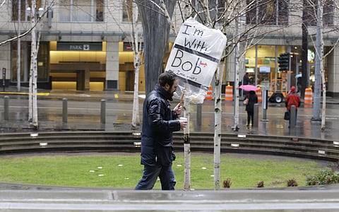 A person walks outside the federal courthouse in Seattle carrying a sign that reads 'I'm with Bob and Immigrants,' in reference to Washington state Attorney General Bob Ferguson, Friday, Feb. 3, 2017, during a hearing in federal court. | AP
