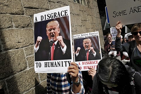Members of International Migrants Alliance in Hong Kong hold placards during a protest against U.S. President Donald Trump's selective country travel ban outside of the U.S. Consulate in Hong Kong, Sunday, Feb. 5, 2017. (Photo | AP)