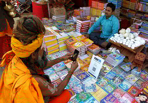 a Hindu holy man pays the vendor through Paytm, a digital wallet company, after buying a book. (File | Reuters)