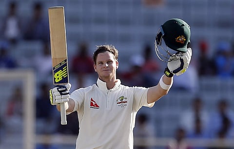Australia's captain Steven Smith raises his bat and helmet to celebrate scoring a century during the first day of their third test cricket match against India in Ranchi. | AP