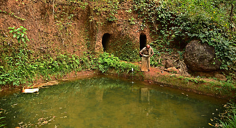 Dhanyachandroji alias Gangadhar Rao (50), who has 20 surangas on his 35-acre agriculture land, walking past a mud tank, also called madhakam, where water from two surangas are collected, at Mulankode near Kundamkuzhi in Bandaduka panchayat in Kasargod.(Al