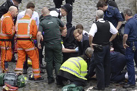 Conservative Member of Parliament Tobias Ellwood, centre, helps emergency services attend to an injured person outside the Houses of Parliament, London. AP
