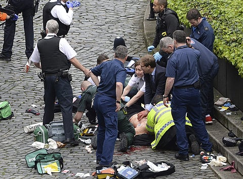 Conservative Member of Parliament Tobias Ellwood, centre, helps emergency services attend to an injured person outside the Houses of Parliament, London, Wednesday, March 22, 2017. | AP