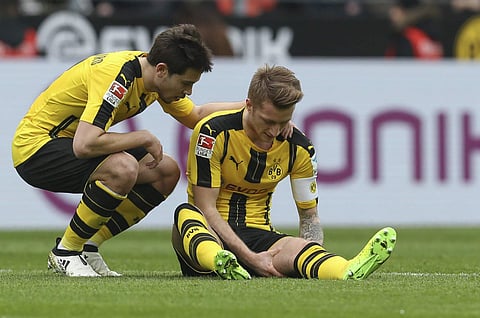 Dortmund's Marco Reus sits injured alongside Raphael Guerreiro, left, curing the German Bundesliga soccer match between Borussia Dortmund and Bayer Leverkusen, in Dortmund, Germany, Saturday, March 4, 2017. | AP