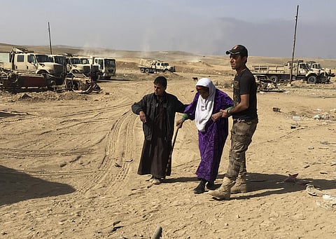 An Iraqi Army soldier helps displaced civilians as they flee their homes due to fighting between Iraqi security forces and Islamic State militants. (Photo | AP)