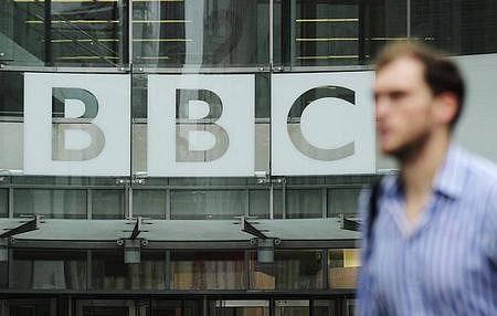 A pedestrian walks past a BBC logo at Broadcasting House in central London. | File Reuters