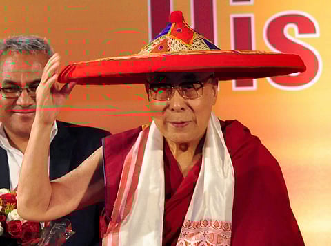Tibetan spiritual leader the Dalai Lama being feliciated with an Assamese Japi during Platinum Jubliee of Assam Tribune Group in Guwahati on Saturday.(Photo | PTI)
