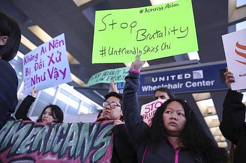 People with Asian community organizations from Chicago hold signs to protest after Sunday's confrontation where David Dao was removed from a United Airlines airplane by Chicago airport police at O'Hare International Airport. (Photo | AP)