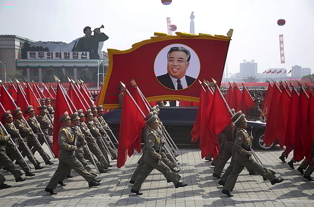 North Korean soldiers carry flags and a photo of late leader Kim Il Sung as they march across Kim Il Sung Square. | AP