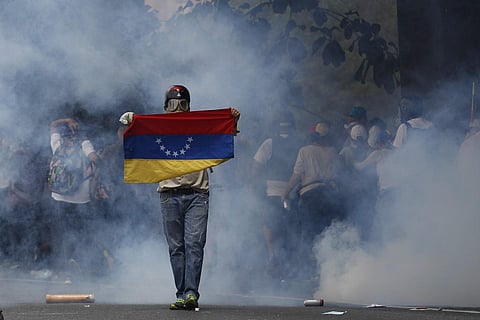 An anti-government protester holds a Venezuelan flag during clashes against security forces in Caracas, Venezuela, Wednesday, April 19, 2017.  | AP