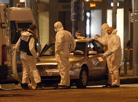 Forensic experts collect evidences from the car belonging to an attacker who killed a police officer on the Champs Elysees avenue in Paris. | AP