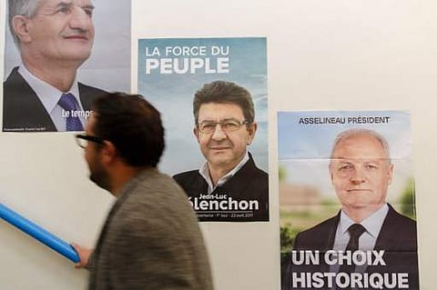 A French voter residing in Hong Kong walks past posters of presidential candidates as he prepares to vote in the first round of France's presidential election at the French International School in Hong Kong on April 23. (Photo | AFP)