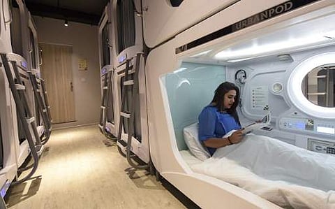 In this photograph taken on April 14, 2017, Indian guest Aditi Ohri poses for a photograph as she reads a magazine in her pod at the Urbanpod hotel in Mumbai. Mumbai's Urbanpod capsule hotel in Mumbai is the first of its kind in India. | AFP