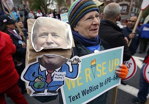 Nancy Kohn, of Boston, holds a Donald Trump puppet and a placard during a May Day rally, Monday, May 1, 2017, in Chelsea, Mass.
