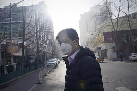 This file photo taken on January 3, 2017 shows a man wearing a mask crossing a street in Beijing. China can avoid three million premature deaths each year if it slashes a type of fine particle air pollution to UN recommended levels, a study said March 15,