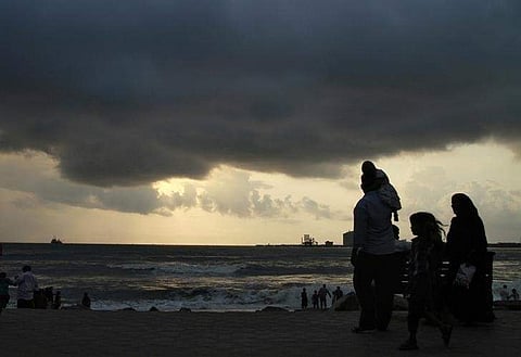 Beachgoers stroll along the Fort Kochi beach as clouds hover over the Arabian Sea in Kerala May 23, 2013. | Reuters