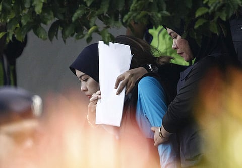 Vietnamese suspect Doan Thi Huong, center in blue, is escorted by police officers out from Sepang court in Sepang, Malaysia. AP