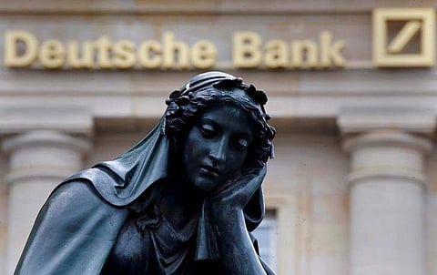 A statue is seen next to the logo of Deutsche Bank. (File | Reuters)