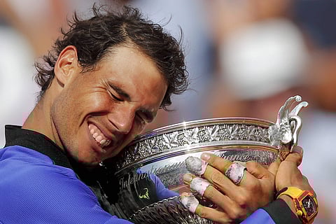 Spain's Rafael Nadal holds the trophy as he celebrates winning his tenth French Open title against Switzerland's Stan Wawrinka in three sets 6-2 6-3 6-1 during their men's final match of the French Open tennis tournament at the Roland Garros stadium in Pa