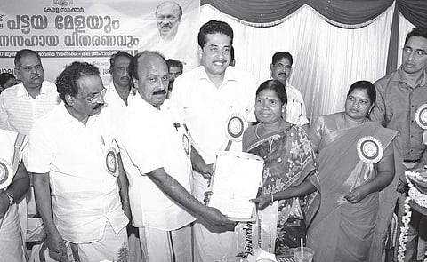 Revenue Minister E Chandrasekharan distributing title deeds to an Adivasi beneficiary at the ‘pattayamela’ held at the KILA hall at Agali, Attappadi, on Monday. A K Balan, Minister for Development of Scheduled Castes and Scheduled Tribes, is also seen