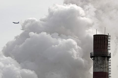 FILE- In this Feb. 28, 2017 file photo, a passenger airliner flies past steam and white smoke emitted from a coal-fired power plant in Beijing.(AP)