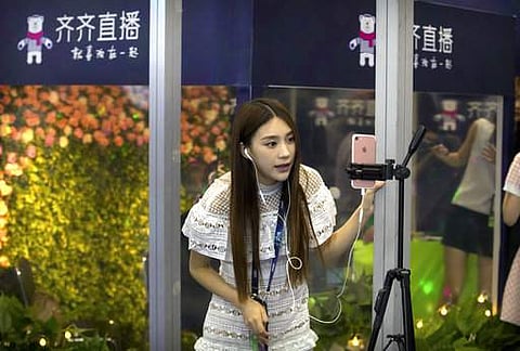 A woman uses a smartphone app to live-stream a video of herself at a corporate booth at the Global Mobile Internet Conference in Beijing on April 27. (File Photo | AP)