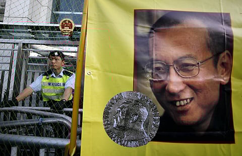 In this Dec. 5, 2010 file photo, a police officer stands guard beside a picture of jailed Chinese dissident Liu Xiaobo outside the Chinese government liaison office in Hong Kong. Jailed Chinese Nobel peace laureate Liu has been released on medical parole 