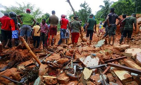 Sri Lankan military rescuers and villagers stand on the debris of a house that was destroyed in a landslide in Bellana village in Kalutara district, Sri Lanka. (File photo | AP)