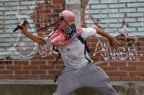A protester winds up to throw a bottle at national guard soldiers during a march against hunger in Caracas, Venezuela, Saturday, June 3, 2017. (AP)