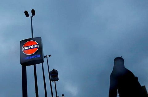 A woman walks past a logo of Indian Oil outside a fuel station in New Delhi. (File | Reuters)