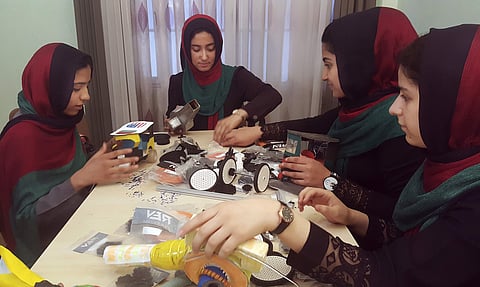 FILE- In this Thursday, July 6, 2017, file photo, teenagers from the Afghanistan Robotic House, a private training institute, practice at the Better Idea Organization center, in Herat, Afghanistan. U.S. President Donald Trump intervened to allow the group